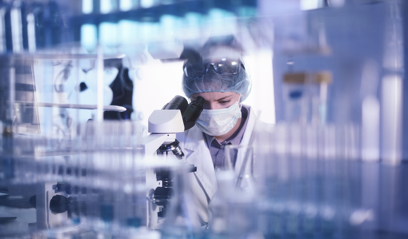 Female microbiologist studying coronavirus with microscope. Credit: iStock/janiecbros