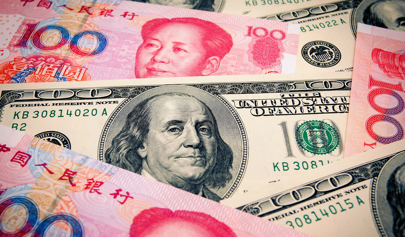 A top-down shot of the Chinese Yuan 100 note and American $100 bill overlayed. iStock/hudiemm