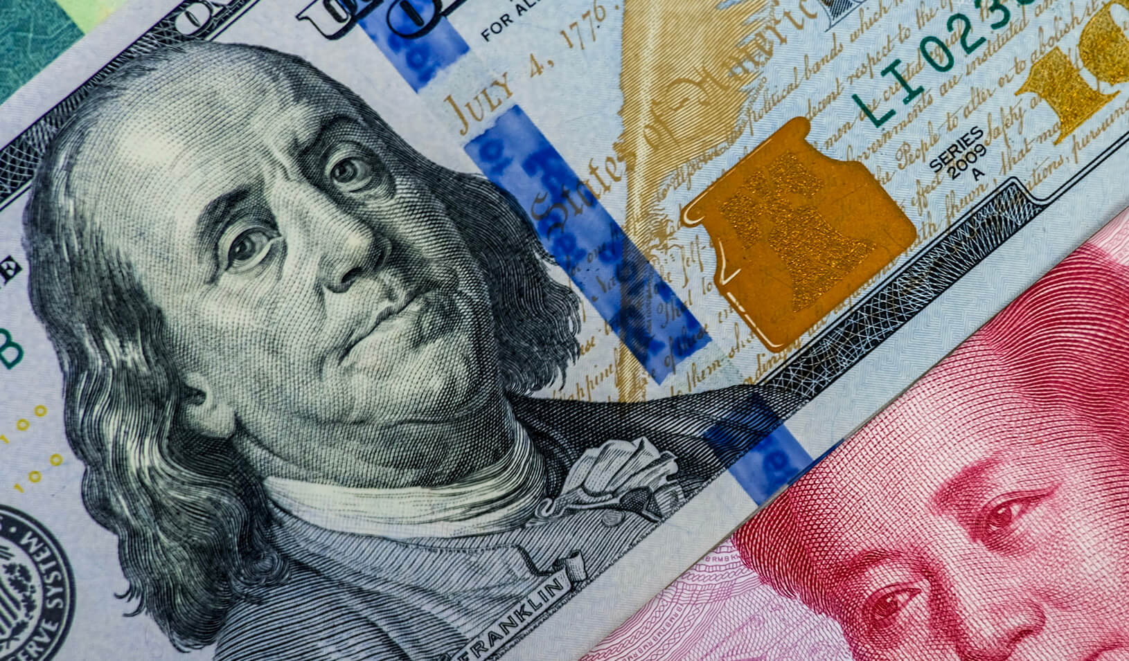 A close-up of a hundred dollar bill almost entirely covering a Chinese Yuan. iStock/Dilok Klaisataporn