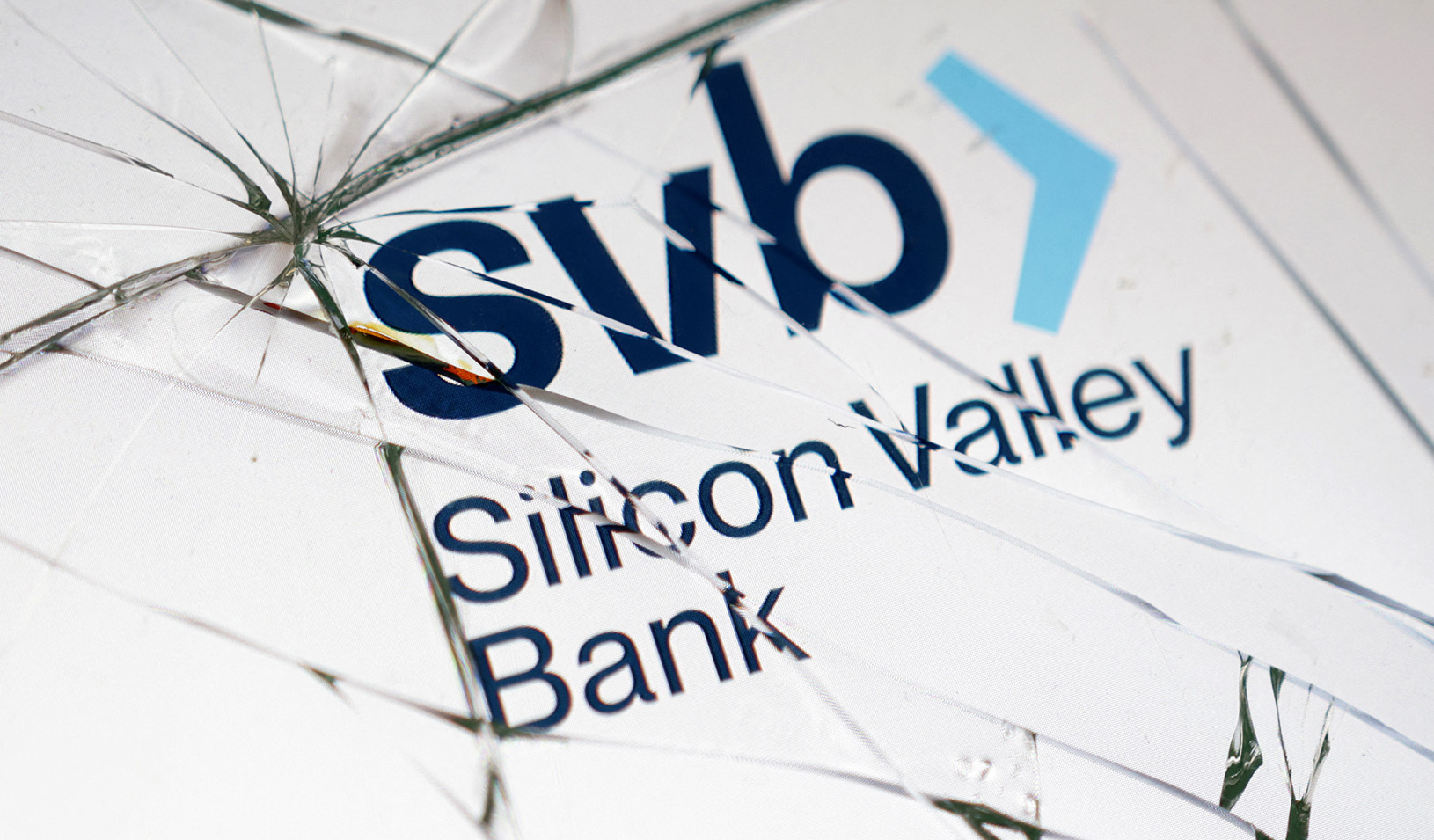 Silicon Valley Bank (SVB) logo is seen through the broken glass of an ATM machine. Reuters/Dado Ruvic