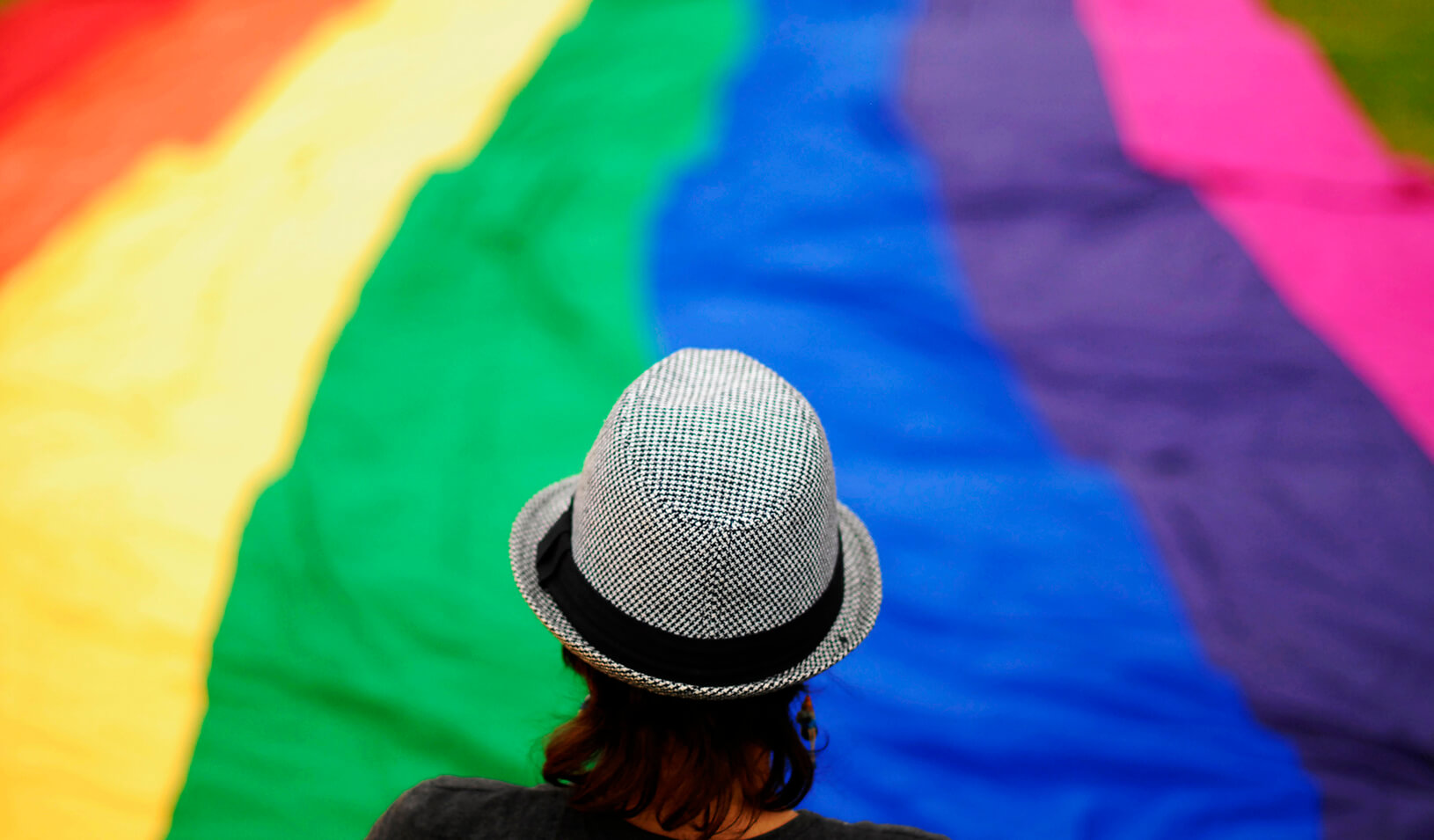 A transgender person overlooks a large rainbow banner