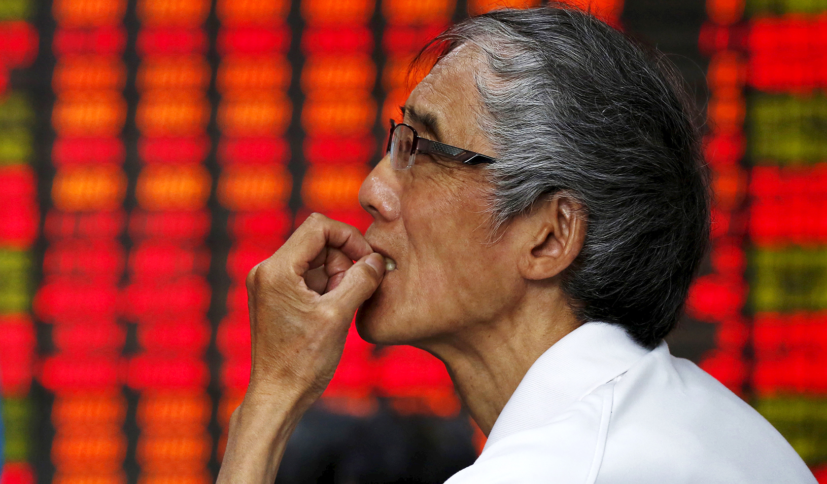 An investor looks at an electronic board showing stock information at a brokerage house in Shanghai, China, on July 10, 2015. | Reuters/Aly Song