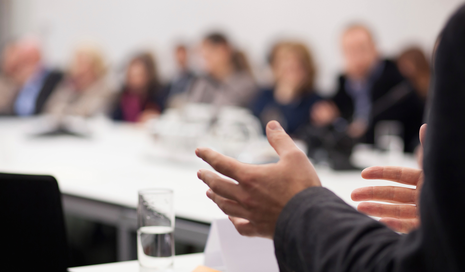 A person's hands gesturing while he or she is speaking at a meeting. | iStock/aerogondo