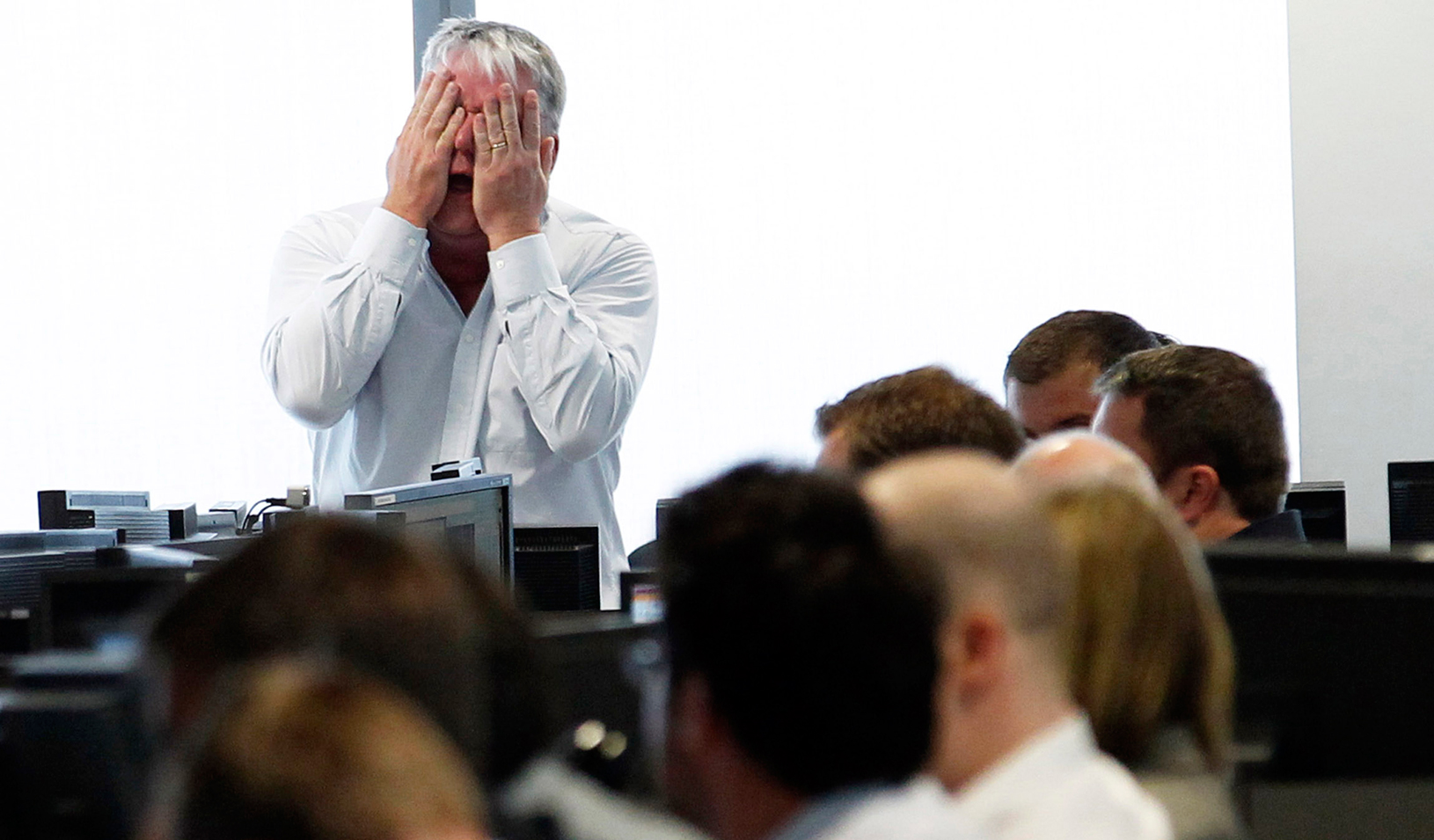 A man holding his hands over his face at work. | Reuters/Luke MacGregor 