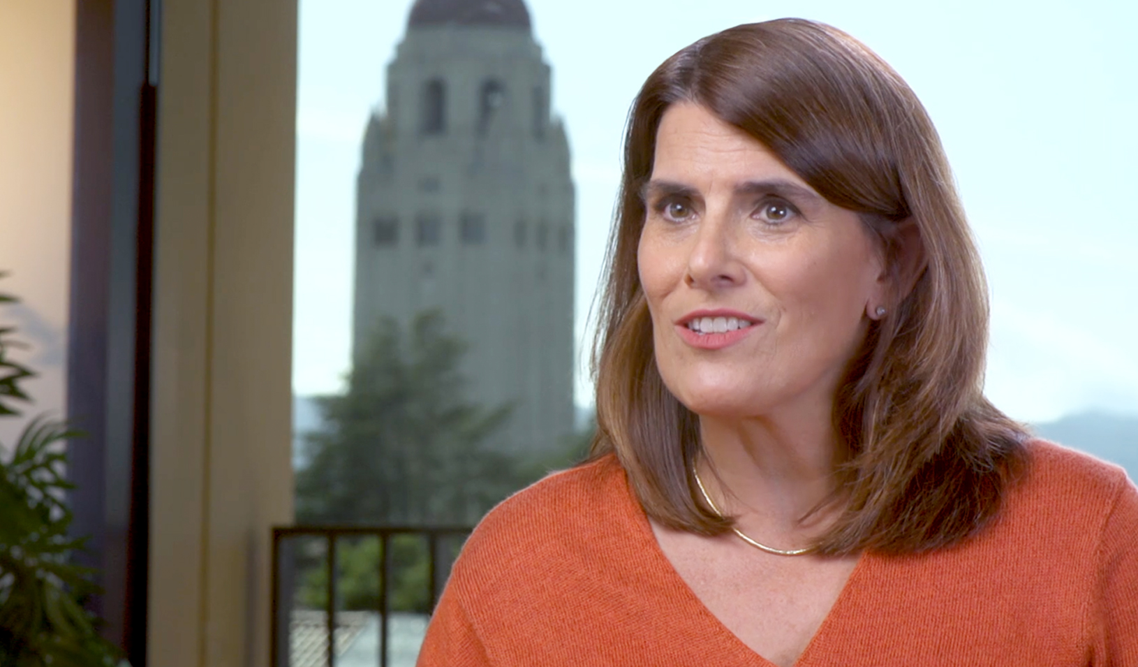 Alt: Stanford GSB Professor Sara Singer speaking to camera with Stanford Hoover Tower in the background. Credit: Video by Mike Elwell