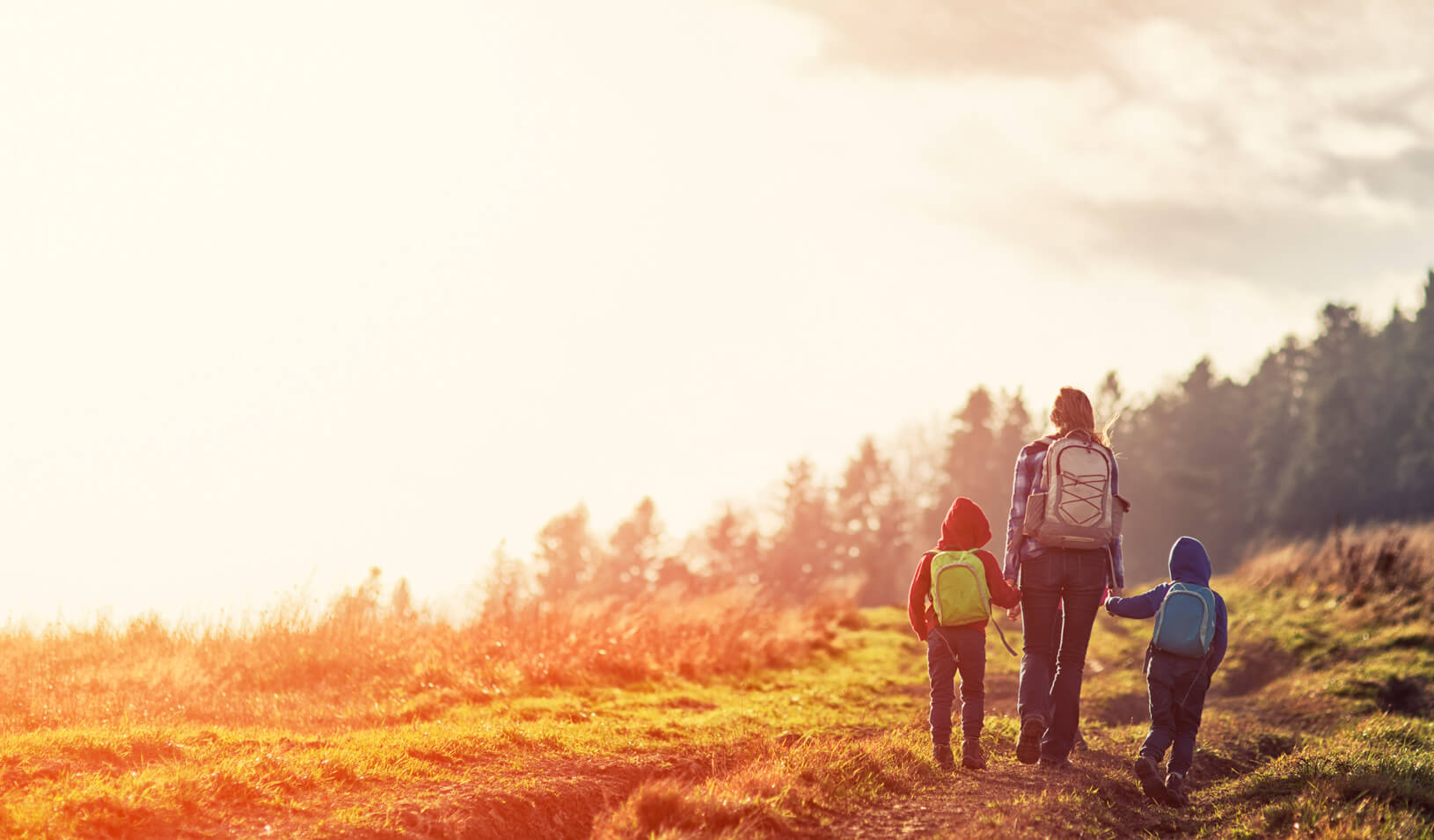 A woman hiking with her children|iStock/Imgorthand