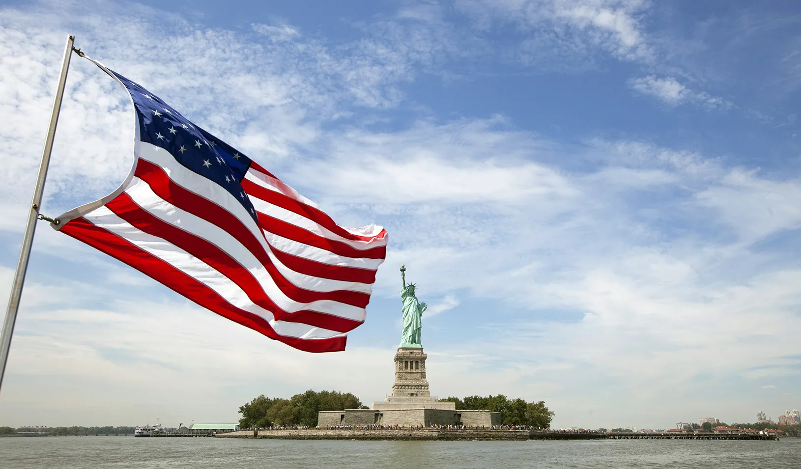 The statue of liberty in the center of the frame, with an American flag waving in the foreground. Reuters/Lucas Jackson