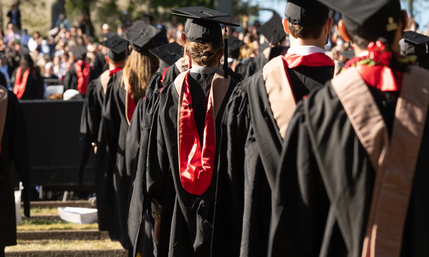 a photo looking at Stanford GSB grads from behind, as they face the stage in the graduation ceremony. | Best Grads