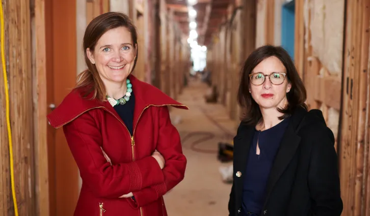 Rebecca Foster, MBA ’05 and Liz Givens, MBA ’04, stand in the hallway under construction. Credit: Drew Kelly