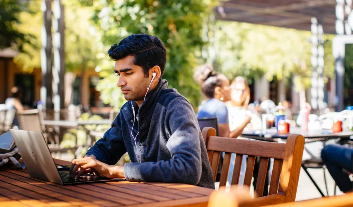 A student works outside at Stanford GSB. | Credit: Elena Zhukova.