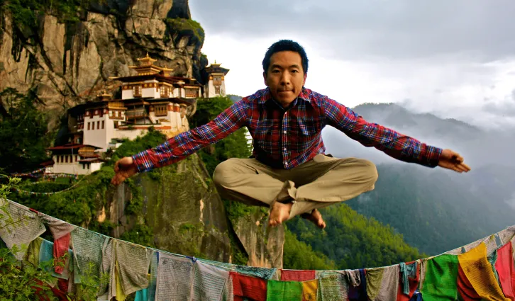 Stephen Lee jumps into a pose with the mountains of Bhutan in the background. Credit: Courtesy of Stephen Lee