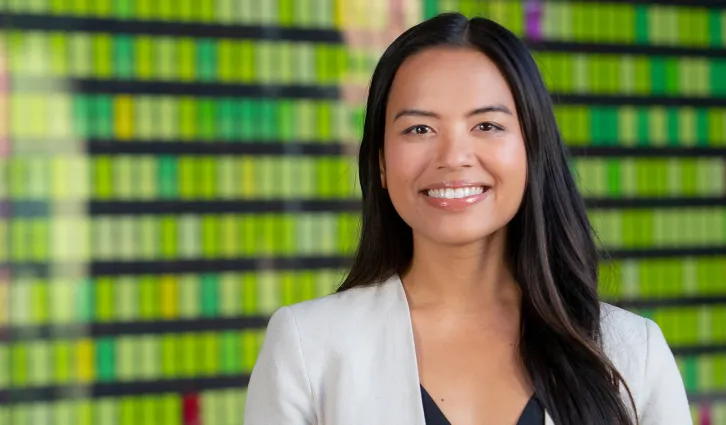 Bright and colorful portrait of Leia de Guzman smiling in front of the change wall at Stanford GSB. Photo by Saul Bromberger