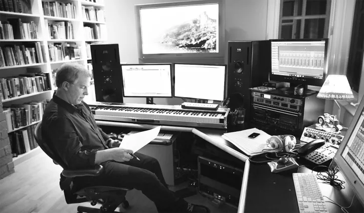 John Graham, MBA ’87, sitting in his home studio looking at sheet music. Courtesy of John Graham