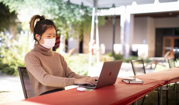 A student working in an outdoor study space at Stanford GSB. Credit: Elena Zhukova