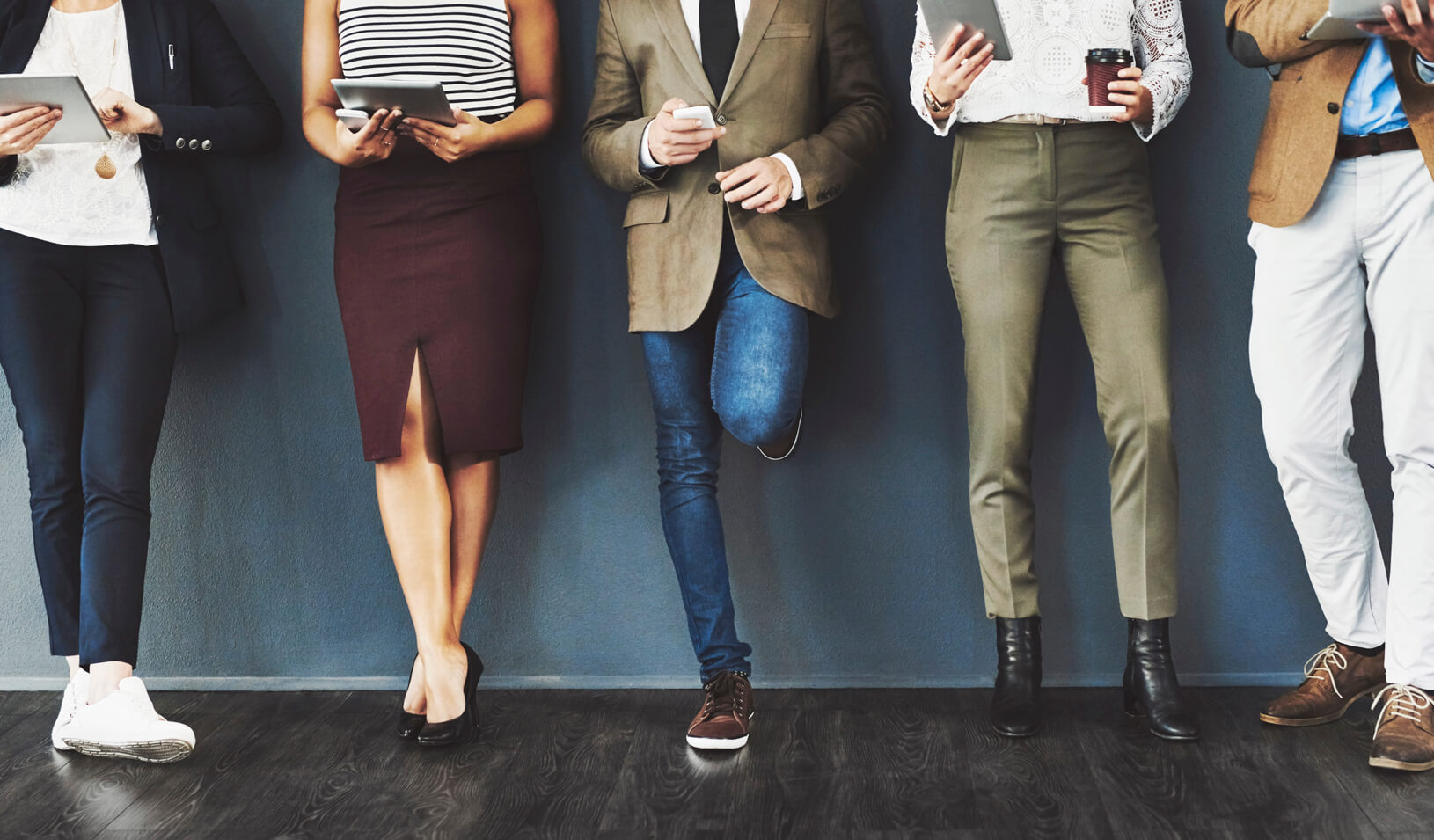 Five business people reading on their phones and tablets. Credit: iStock/peopleimages